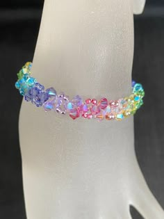 a white mannequin head wearing a bracelet with multicolored beads on it