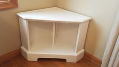 a white corner shelf sitting on top of a wooden floor next to a window in a room