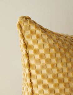 a close up of a yellow pillow on a white surface with no one in it