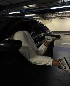 a man sitting in the driver's seat of a car with his foot on the door handle