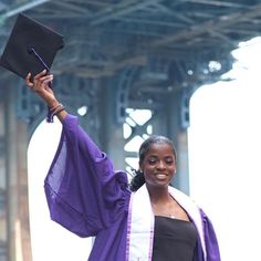 a woman in graduation gown holding up her cap and gown