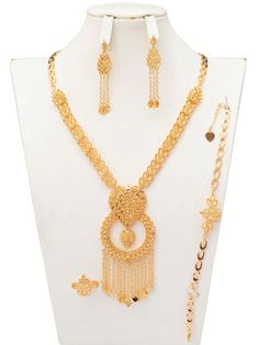 a white mannequin with gold jewelry set on it's neck and two necklaces