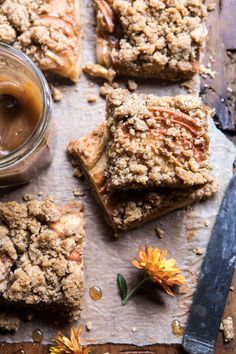 several pieces of dessert sitting on top of a piece of parchment paper next to a jar of peanut butter