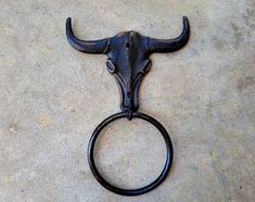 an ox's head mounted to the wall with a ring on it that is sitting on concrete