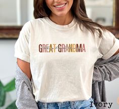 a woman wearing a white shirt with the words great grandma in multicolored letters