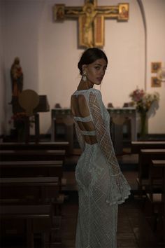 a woman in a white dress standing in front of pews