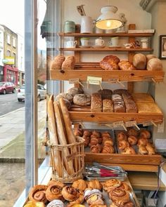 an assortment of breads and pastries on display in a store window with other items