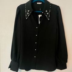 Black Button-Up Top. Festive Sparkle Embellishments Collar And Buttons. It’s So Fun And Versatile!! Channel Your Inner Elvis With Some Bell Bottoms And Boots Or Keep It Classic With A Maxi Skirt And Pumps. Black, Rhinestone, Pearls, Collar, Button Up. Size Large. Never Worn, Like New! No Tags. Colors May Vary Due To Lighting. Measurements Are Approximate. Elegant Button-up Embellished Blouse, Elegant Embellished Button-up Blouse, Embellished Button-up Workwear Blouse, Party Tops With Pearl Buttons And Long Sleeves, Long Sleeve Party Tops With Pearl Buttons, Chic Party Blouse With Pearl Buttons, Long Sleeve Blouse With Pearl Buttons For Party, Formal Black Embellished Blouse, Black Long Sleeve Tops With Embellished Collar