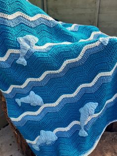 a blue crocheted blanket sitting on top of a tree stump