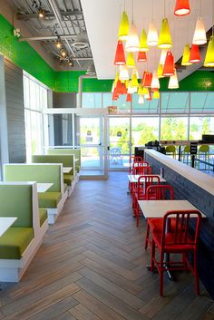 an empty restaurant with colorful lights hanging from the ceiling and green booths on either side