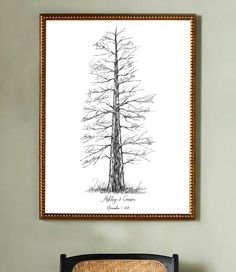 a black and white drawing of a tree in a frame on the wall above a chair