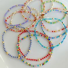 six bracelets with different colored beads on a white surface, one is gold and the other is blue