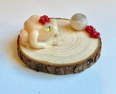 a wooden slice with a small white cat on it's back and a red bow around its neck