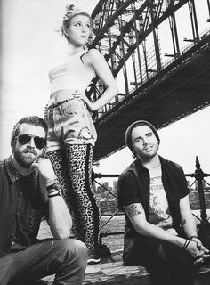 two men and a woman are posing for a photo in front of the sydney harbour bridge