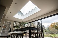 a dining room table and chairs under a skylight