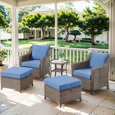 an outdoor living area with blue cushions and wicker furniture on the front porch, surrounded by trees