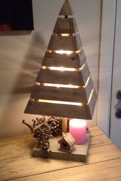 a wooden christmas tree sitting on top of a table next to a candle and other decorations