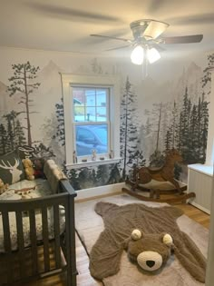 a baby's room with a teddy bear rug, crib and rocking chair