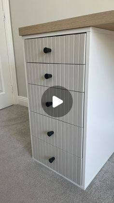 a white cabinet with black knobs and a video player on the bottom shelf in front of it