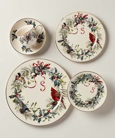 three plates with christmas decorations on them and one has a red bird in the center