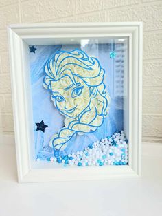 a white frame holding a blue and yellow paper cut out of the face of princess aurora