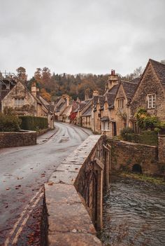 an empty street with houses on both sides and water running down the road in front