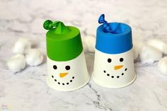 two salt shakers decorated like snowmen on a marble surface