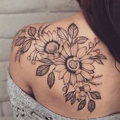 the back of a woman's shoulder with sunflowers and leaves on it