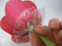 a person is holding a plastic flower in their left hand and wrapped in cellophane