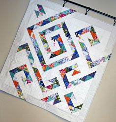 a quilted wall hanging on the side of a white wall with an abstract design