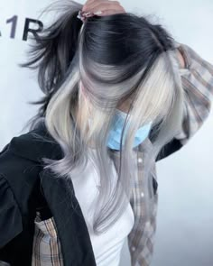 a woman with grey hair is wearing a blue face mask and black jacket while she has her hands on her head