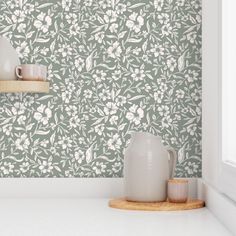 a white vase sitting on top of a counter next to a cup and saucer