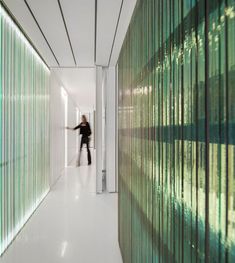 a woman is standing in the hallway between two walls with vertical blinds on each side