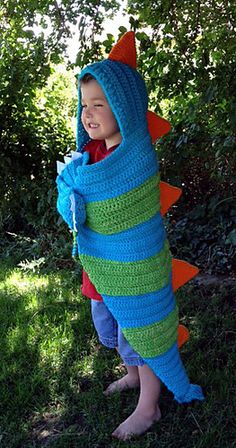 a little boy wearing a crocheted dinosaur costume