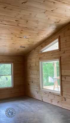 an empty room with wood paneling and three windows