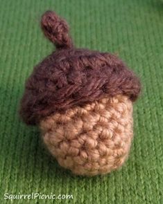 a small crocheted acorn on a green surface