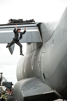 a man hanging off the side of an airplane