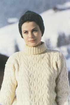 an old photo of a woman wearing a sweater in the snow with her hands on her hips