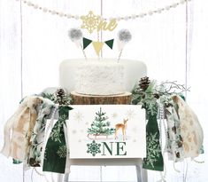 a white cake sitting on top of a wooden table next to a christmas tree sign