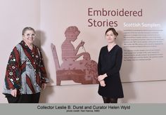 two women standing next to each other in front of a sign