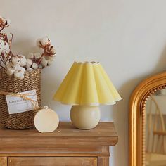 a yellow lamp sitting on top of a wooden table next to a basket filled with cotton