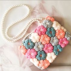 a handbag made out of crochet and beads on a white tablecloth