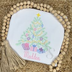 a white plate with a christmas tree and presents on it, surrounded by wooden beads