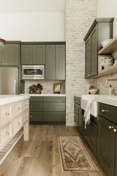 a kitchen with gray cabinets and white counter tops, an area rug on the floor