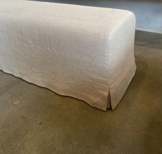 a bed with a white cover on top of it in front of a wall and floor