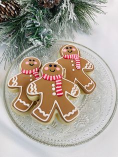 three decorated gingerbread cookies sitting on top of a glass plate