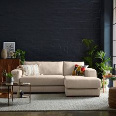 a living room with black walls and white carpeted flooring, a beige sectional sofa sits in front of a coffee table