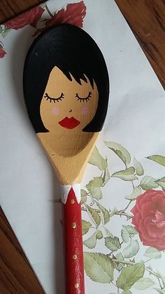 a close up of a wooden spoon with a woman's face painted on it