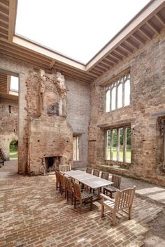 an outdoor dining area with brick flooring and large windows, surrounded by stone walls