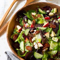 a salad with cucumbers, apples, and pecans in a wooden bowl